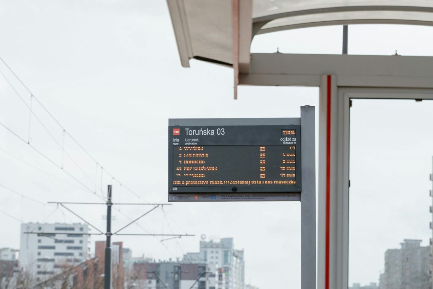 Digital tram stop sign at Toruńska 03 in an urban cityscape setting.