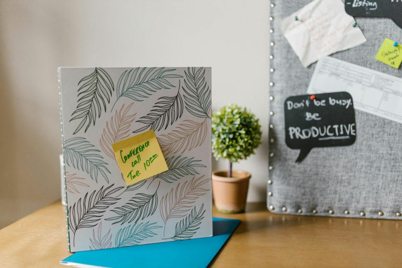 A home office space featuring a notebook with sticky notes beside a motivational bulletin board.