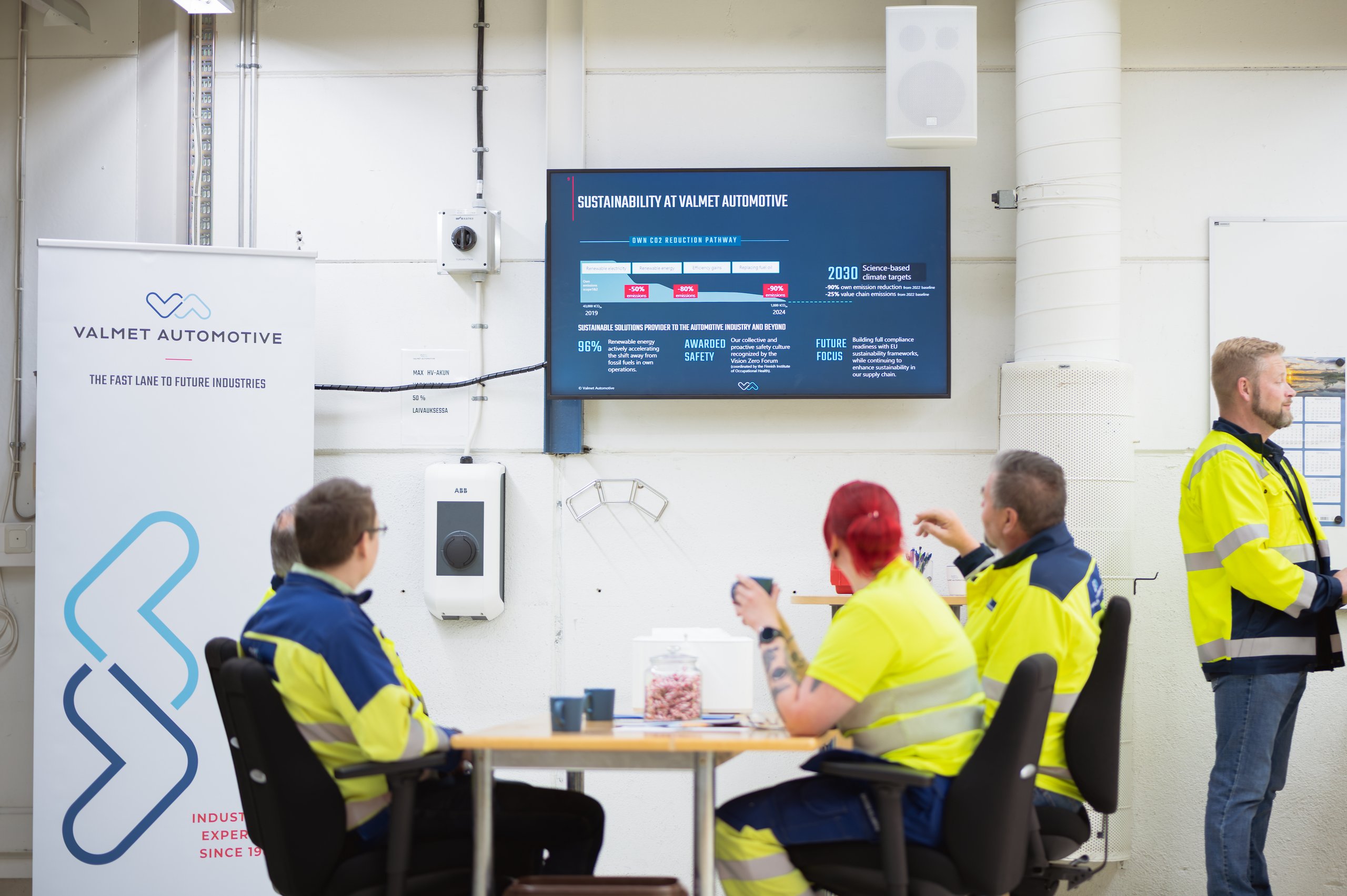 Valmet Automotive team meeting room: team at a table with company content on the wall screen