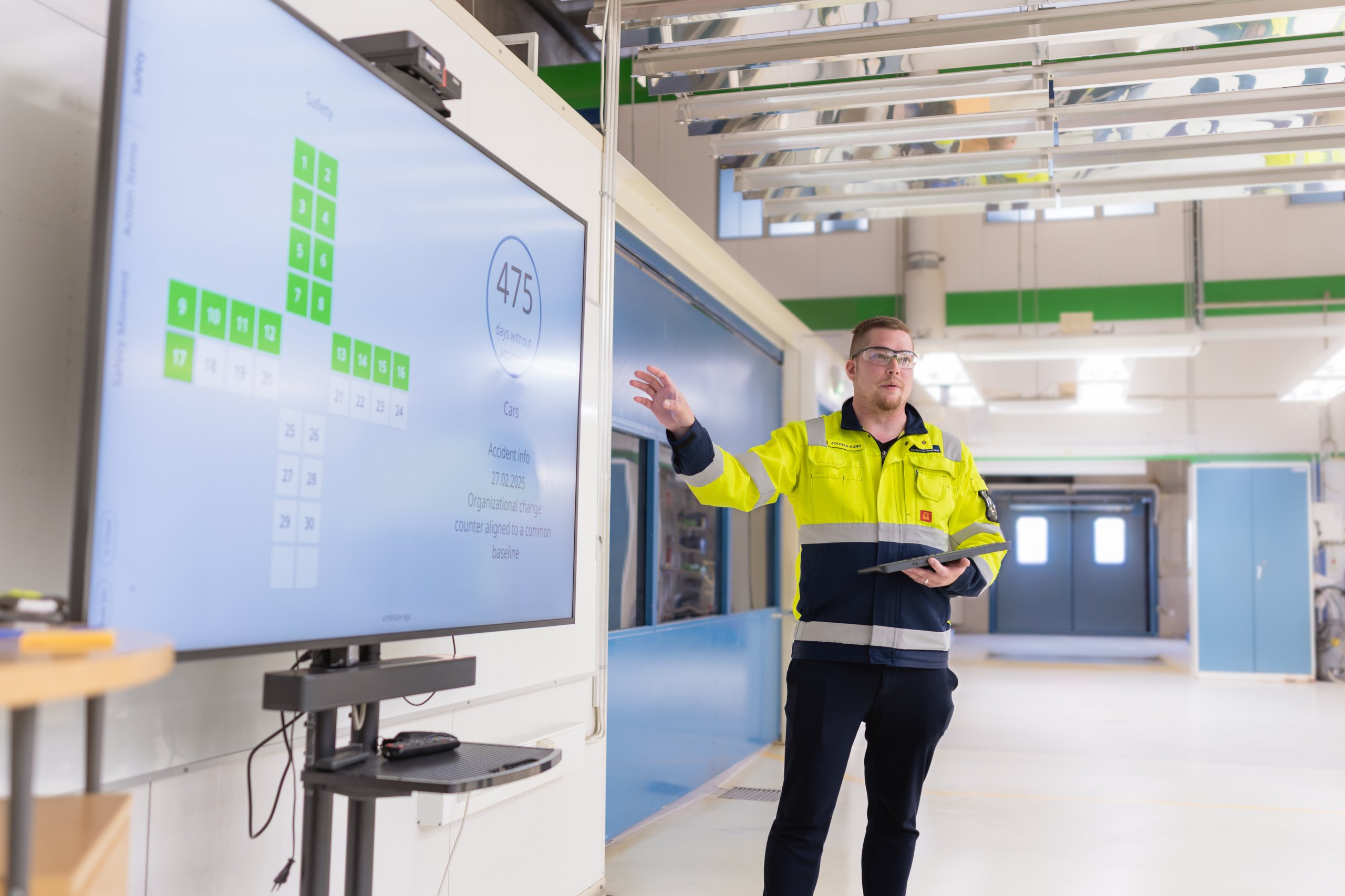 Valmet Automotive shop floor: team leader pointing at the KPI cross on the Digital Tier Board
